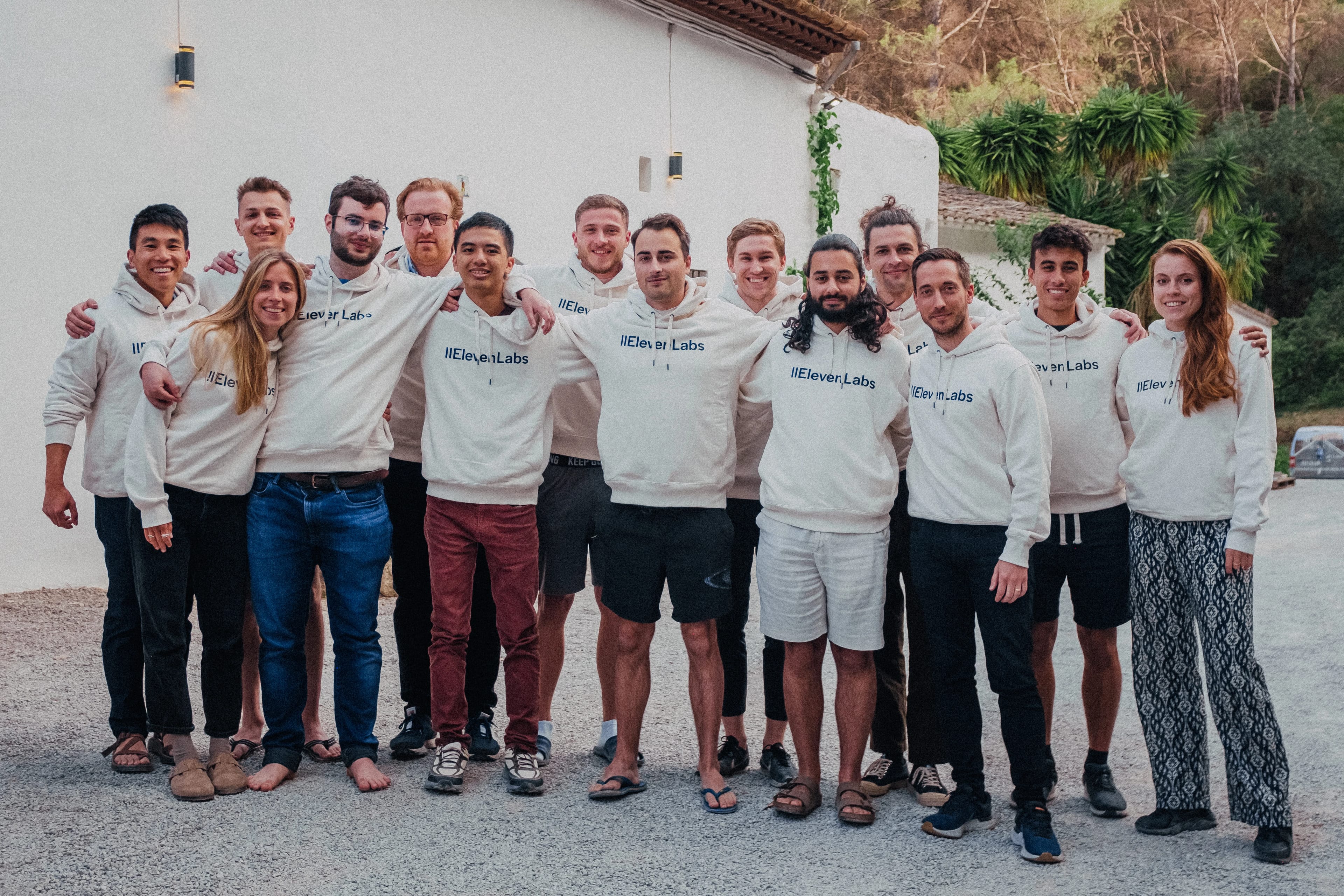 A group of 13 people wearing "Eleven Labs" hoodies, standing together outdoors.