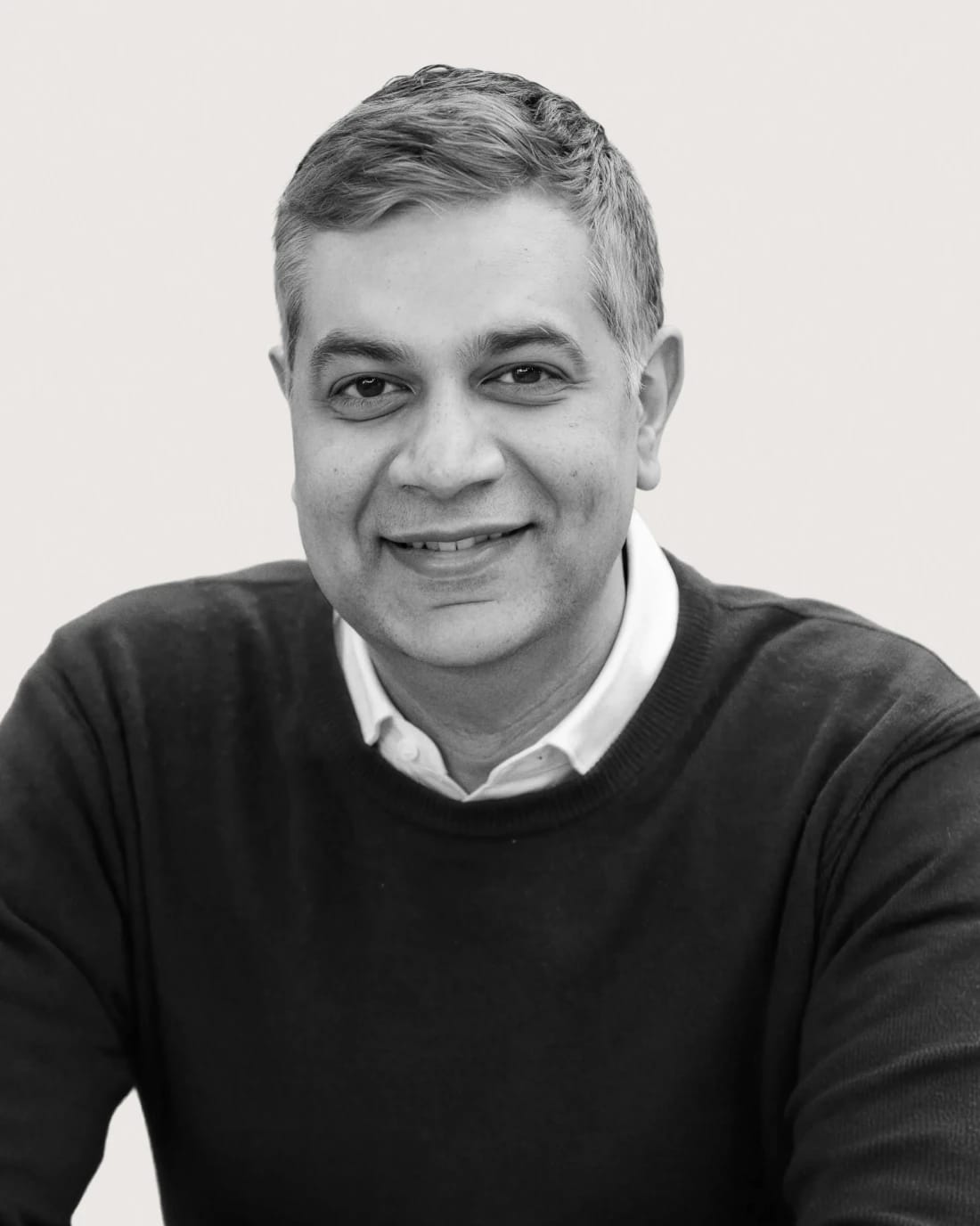 Smiling middle-aged man in a dark sweater and collared shirt.