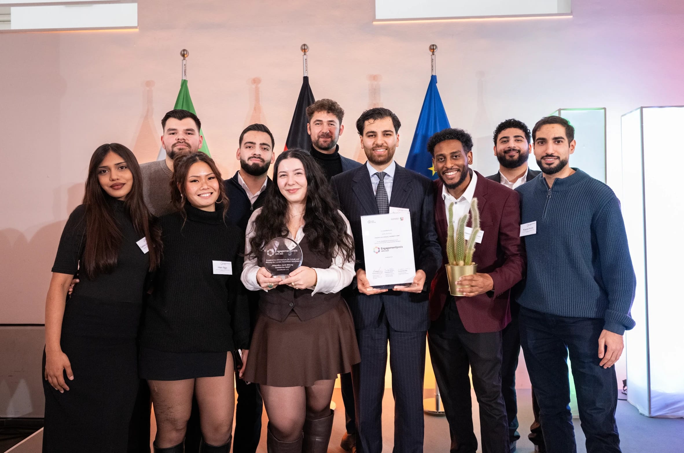 10 students smiling with plaques and a trophee