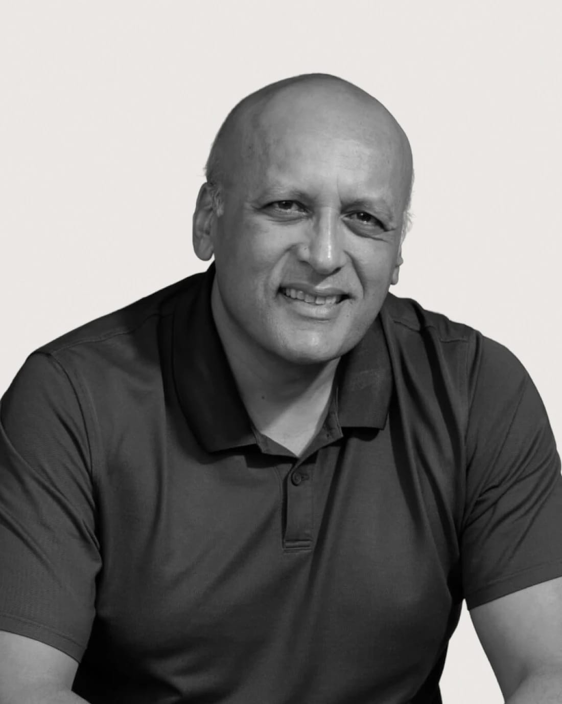 Portrait of a smiling bald man wearing a dark polo shirt.