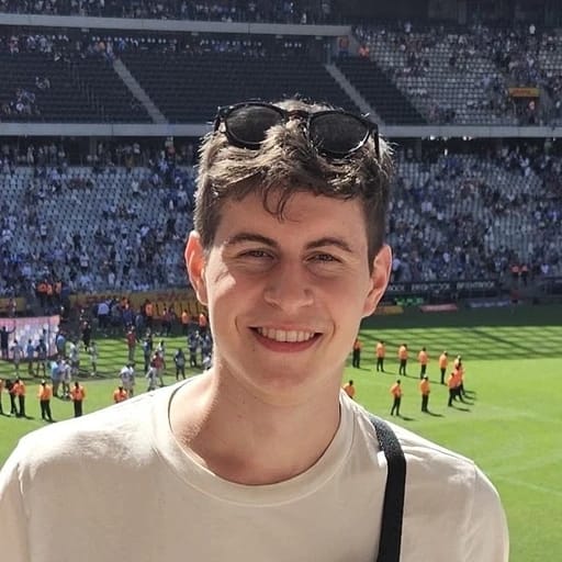 Individual smiling at a stadium event wearing sunglasses on their head.