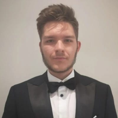 Young man wearing a black tuxedo and bow tie, facing the camera.