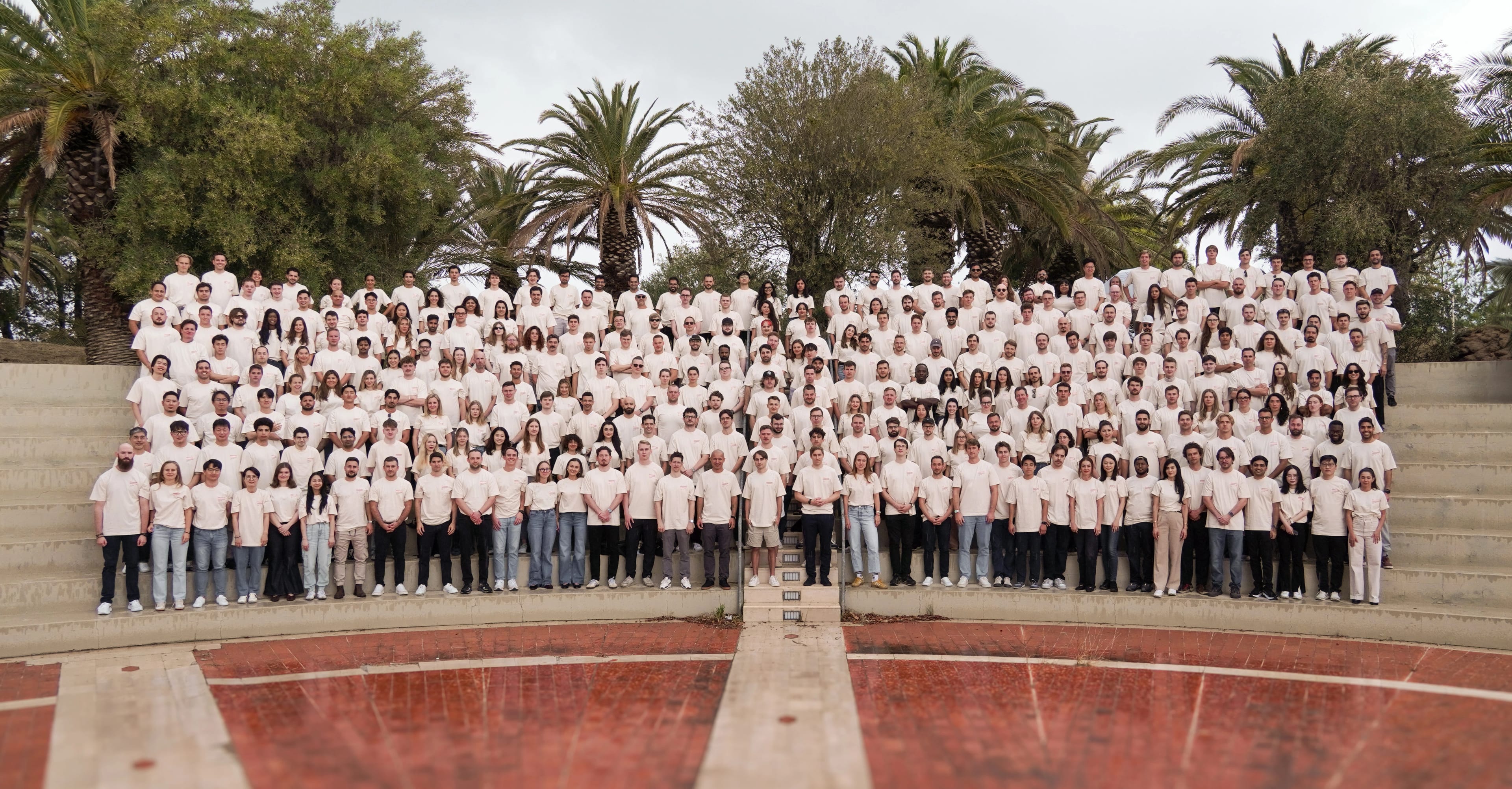 A large group of people wearing matching shirts, posing outdoors on tiered steps.