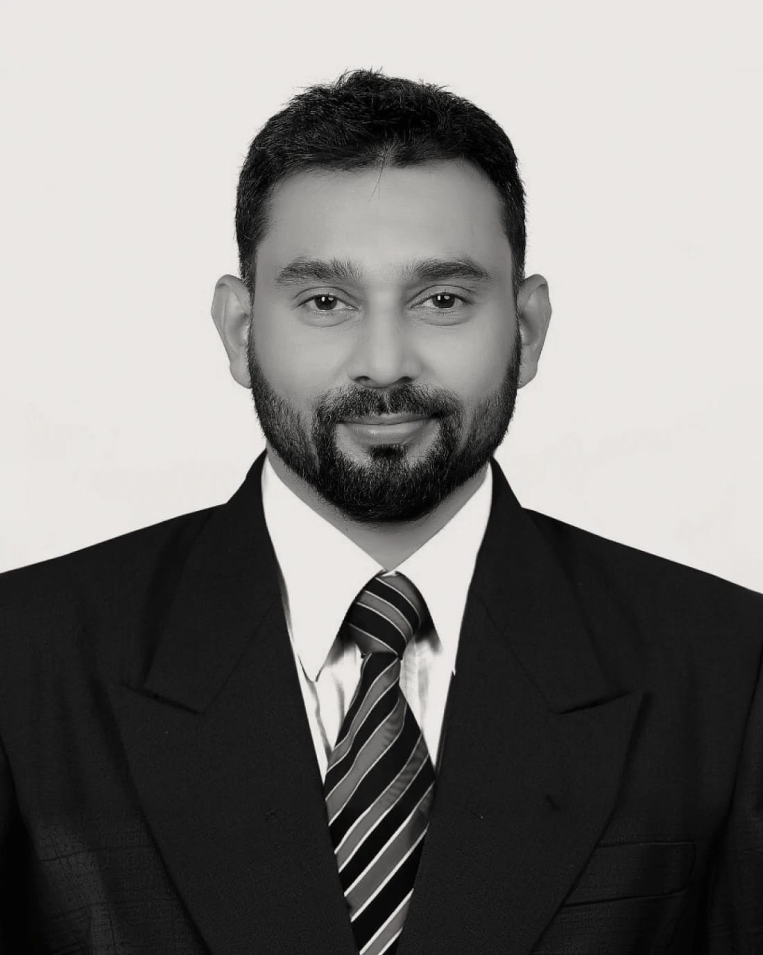 Man in a suit and striped tie with a beard, facing the camera.