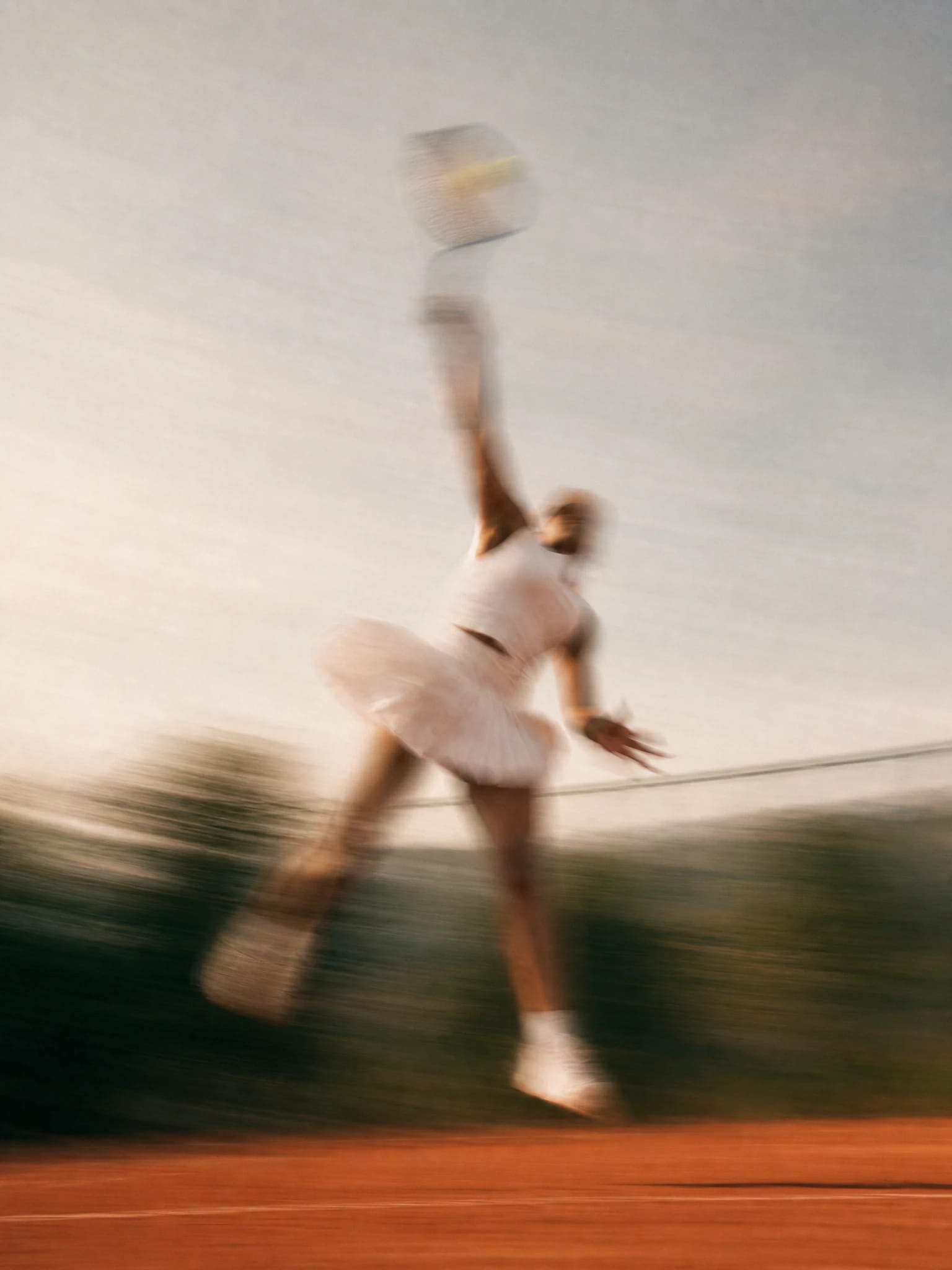 Motion-blurred ballet dancer in a white tutu leaping across a stage.
