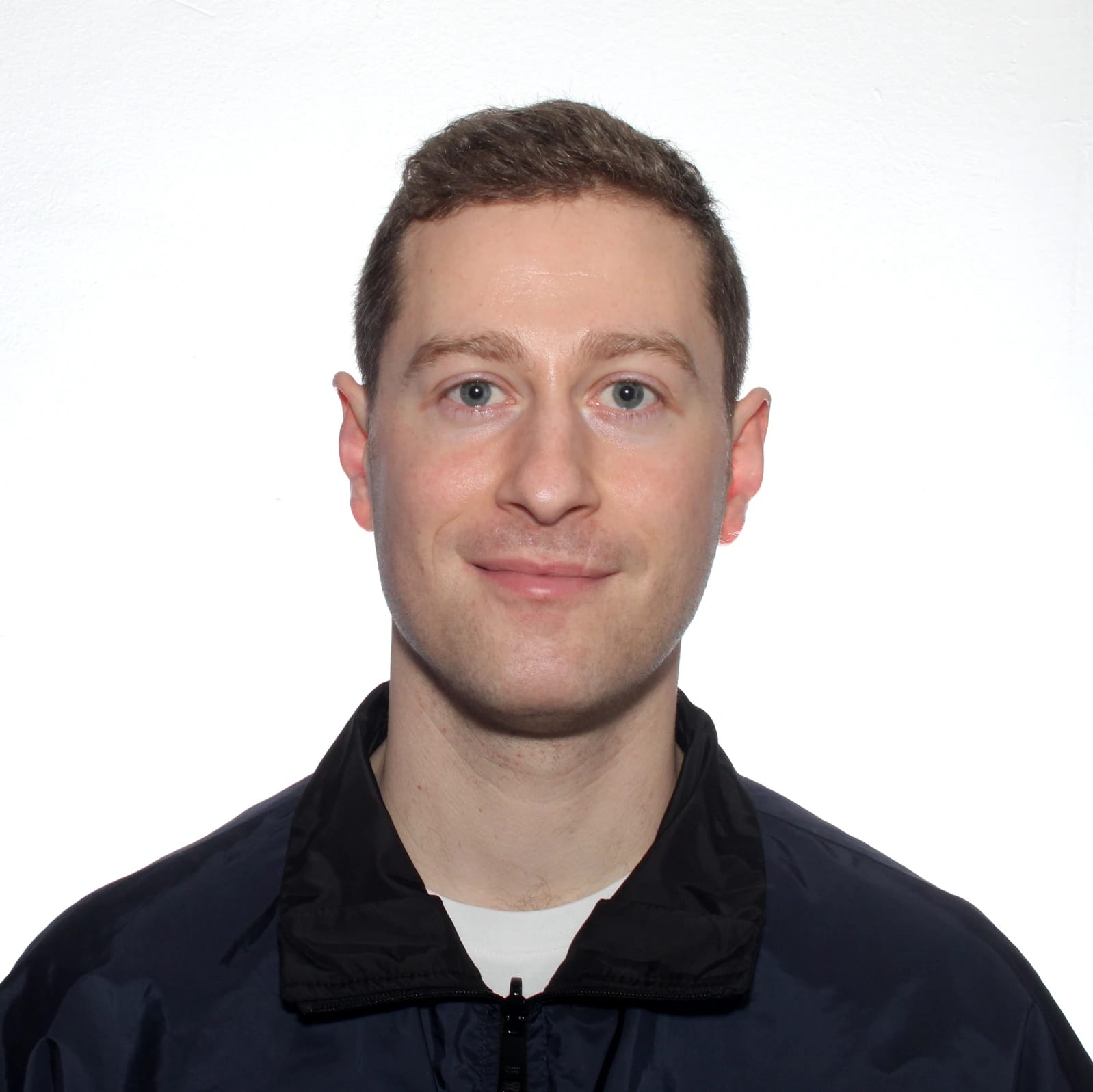 Head-and-shoulders portrait of a smiling man wearing a black jacket