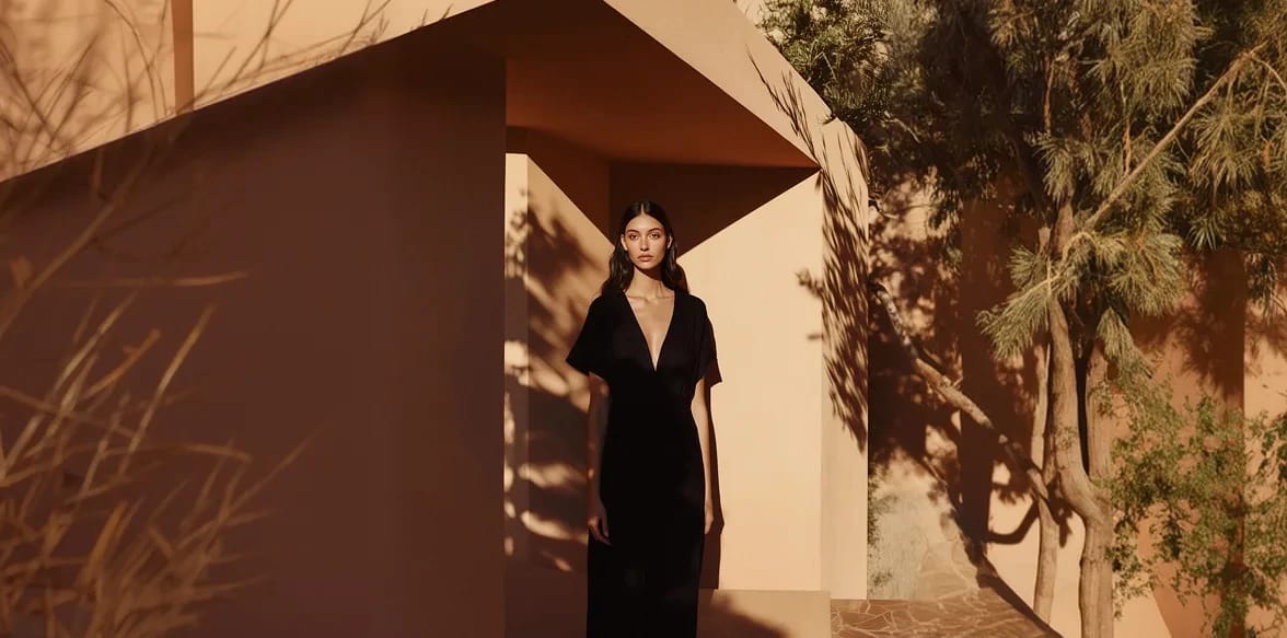 A woman in a black dress standing in a sunlit Moroccan doorway