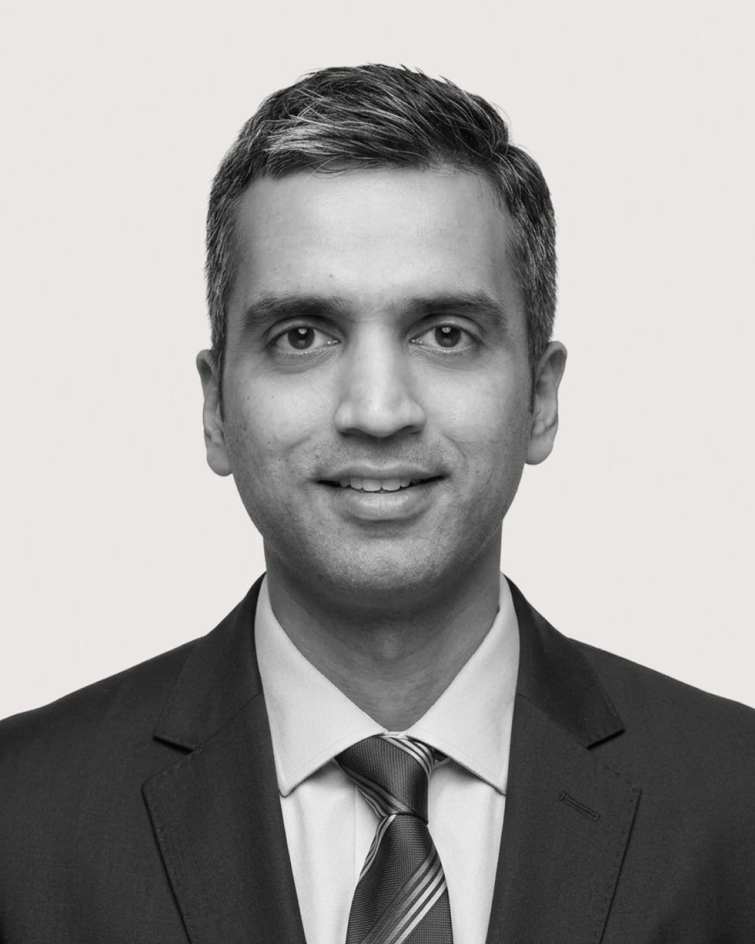 Professional headshot of an unidentified man wearing a suit and tie.