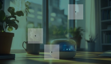 A smart speaker with a digital display on a desk, surrounded by potted plants and books, with a window in the background.