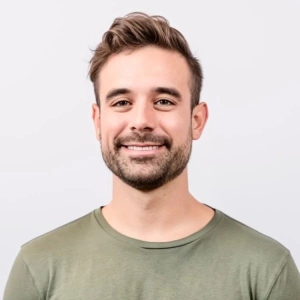 Smiling bearded man in a green shirt against a light background.
