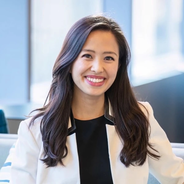 Smiling businesswoman in a white blazer posing in a bright office.
