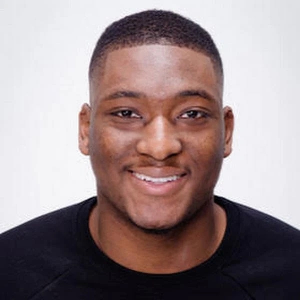Smiling Black man with short hair wearing a black shirt.