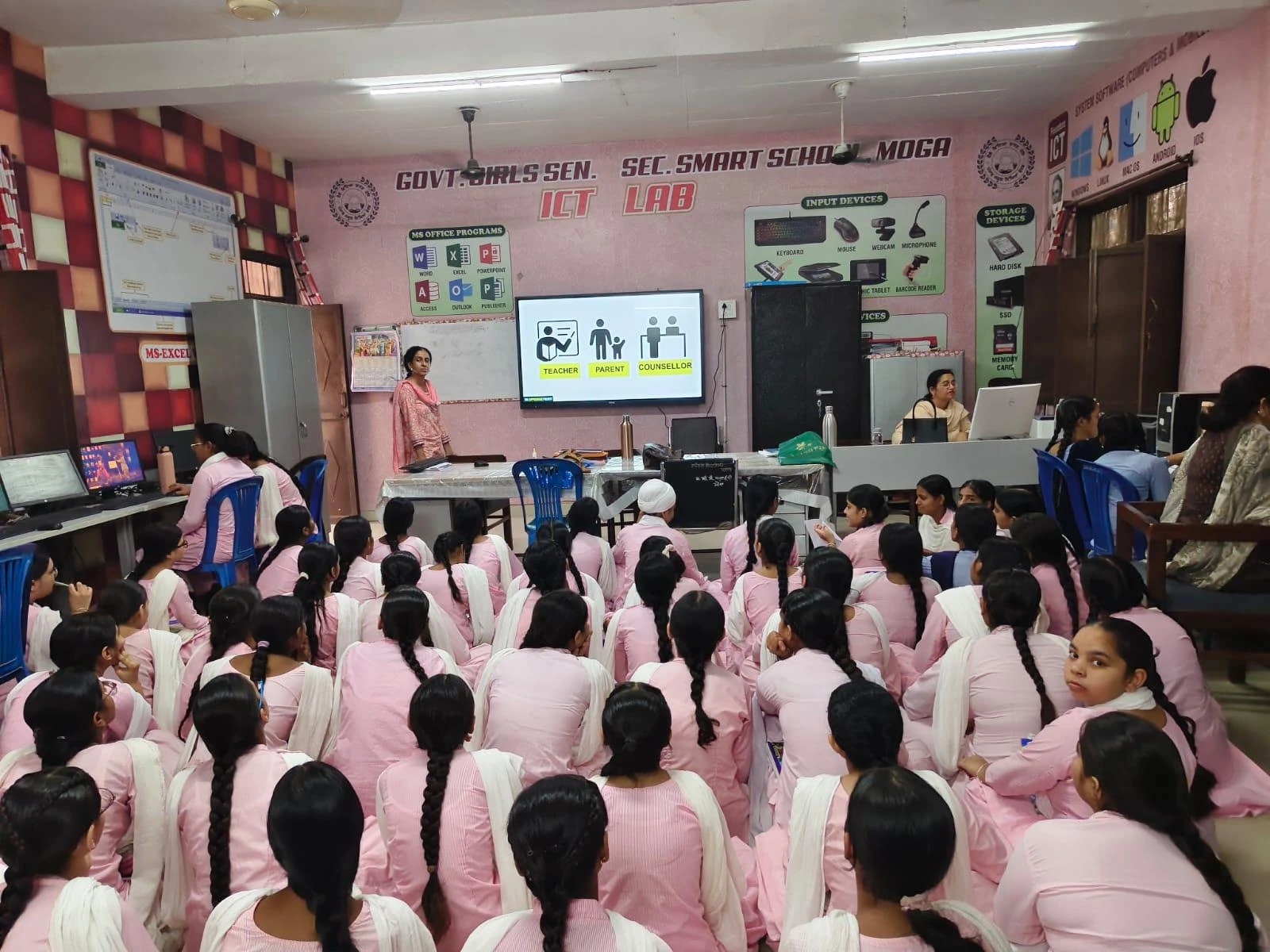 Classroom session with teacher and students in pink uniforms, discussing roles: teacher, parent, counselor.