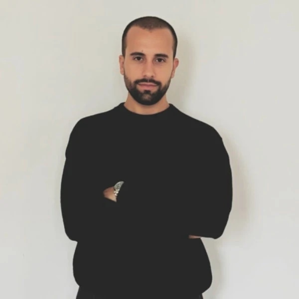 Bearded man in a black shirt standing with his arms crossed.