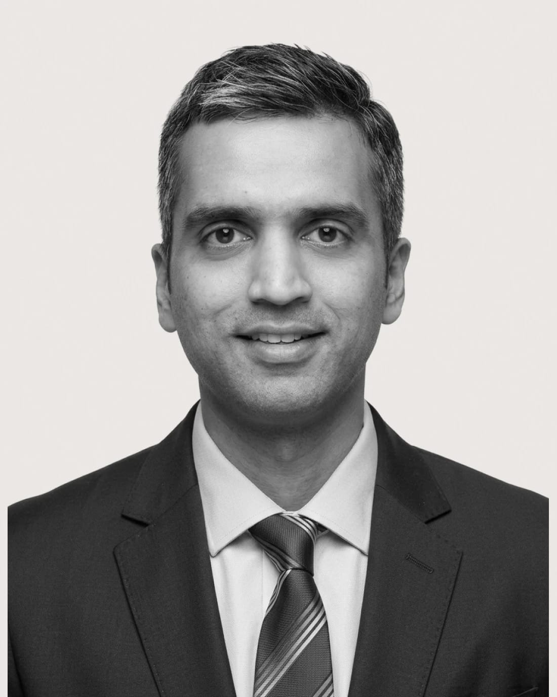 Professional headshot of an unidentified man wearing a suit and tie.