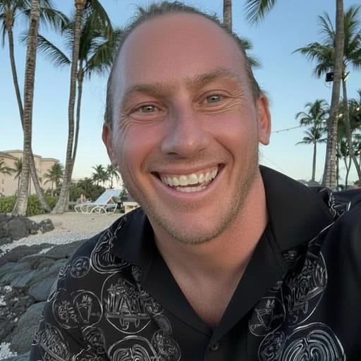 A person smiling with palm trees and a beach in the background.