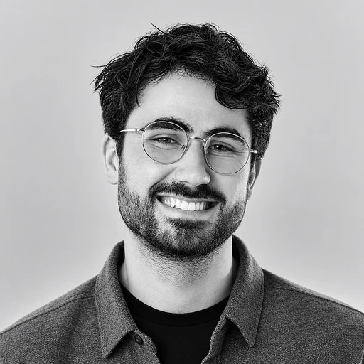 Smiling bearded man wearing glasses and a collared shirt.