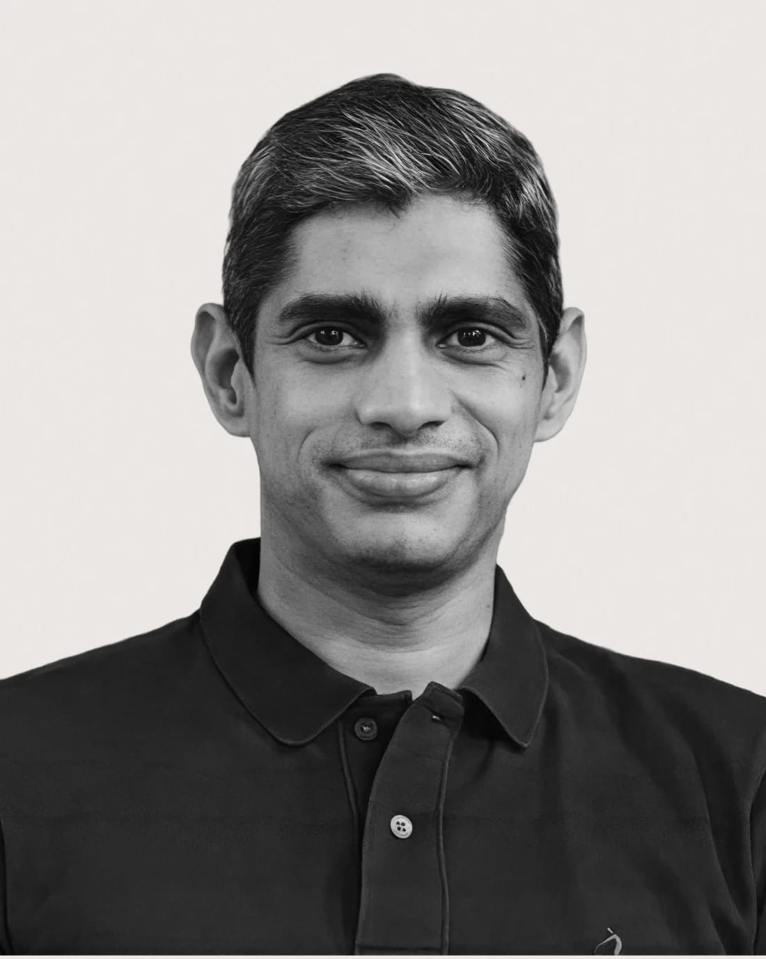 Head-and-shoulders portrait of a smiling man wearing a dark collared shirt.