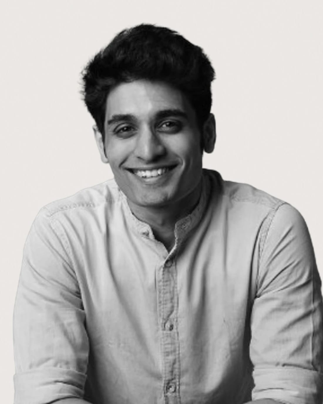 Smiling man in a black suit with arms crossed.