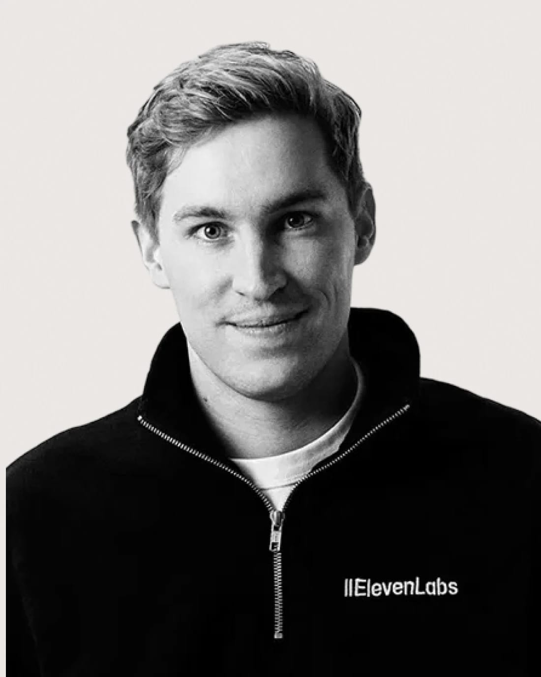 Black-and-white portrait of an ElevenLabs team member wearing a branded jacket.