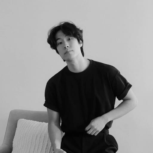 Person in a black T-shirt sitting on a couch, looking at the camera.