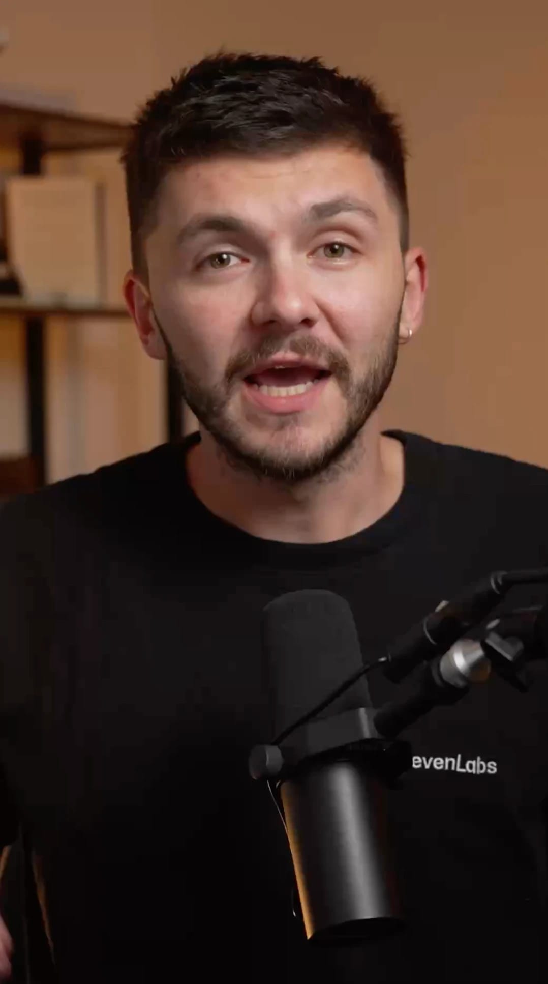 Person speaking into a microphone, wearing a black SevenLabs shirt.