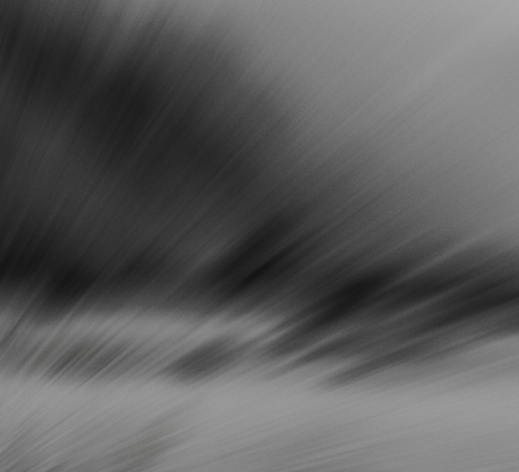 Abstract grayscale texture with diagonal streaks and a soft gradient from dark to light.