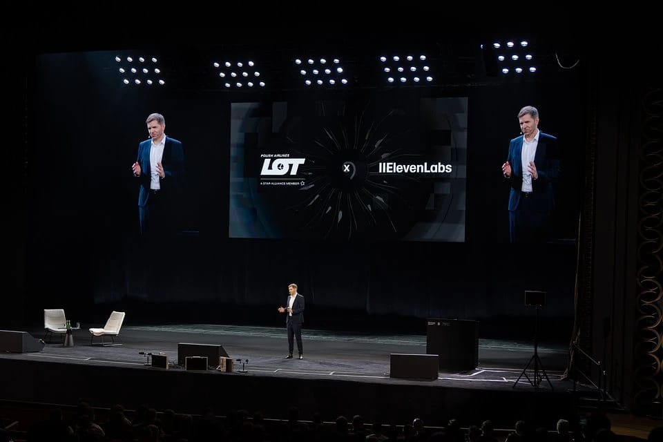 Michał Fijoł, CEO at LOT Polish Airlines on stage with LOT and ElevenLabs logos displayed on a large screen.