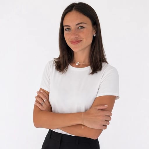 Smiling woman in a white shirt standing with her arms crossed.