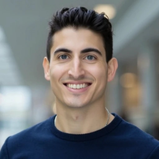 Smiling young man with dark hair wearing a navy sweater.