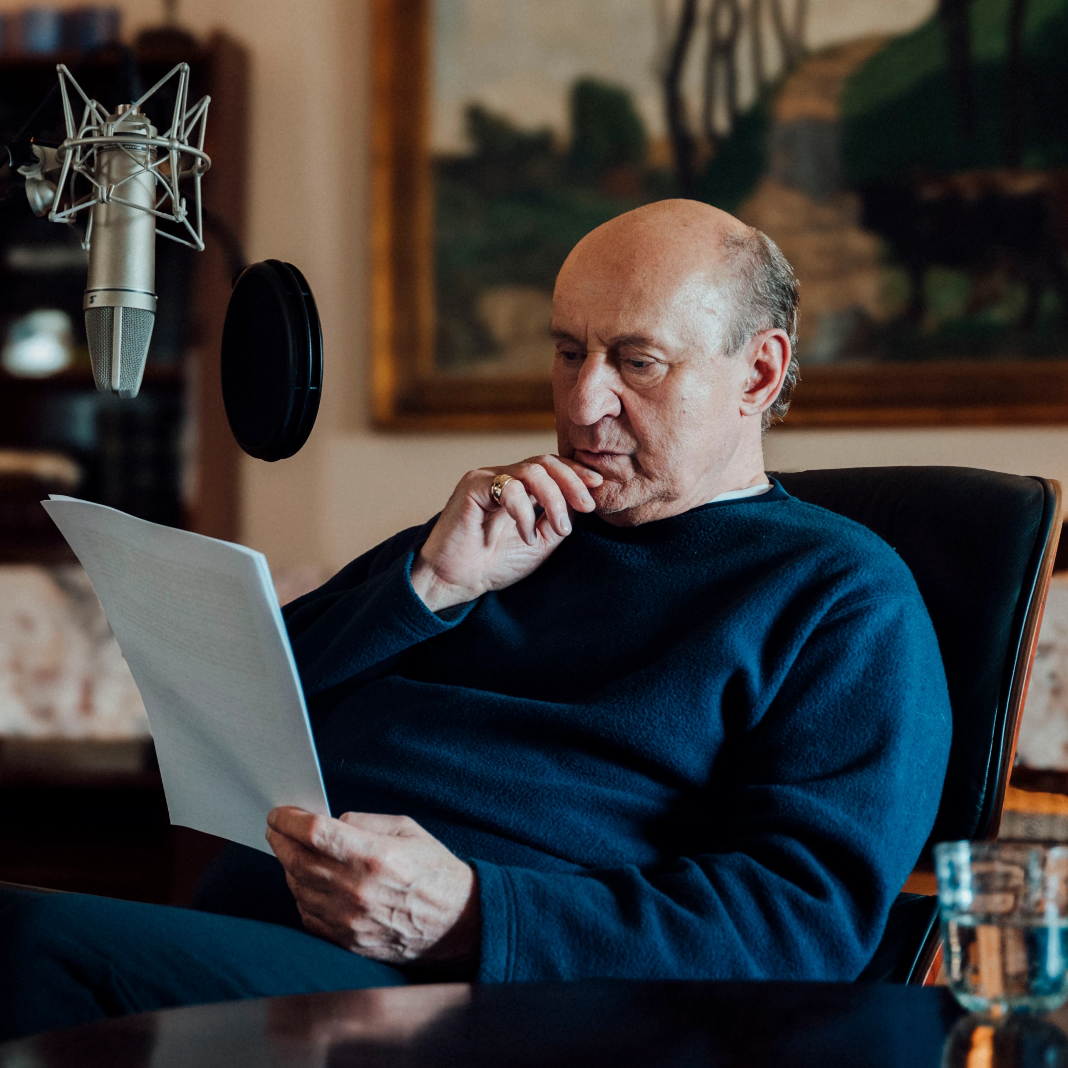 Piotr Fronczewski sitting in an armchair studying a printed script