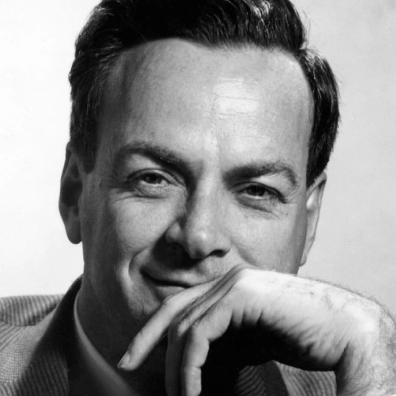 A man with dark hair, smiling slightly, resting his chin on his hand.